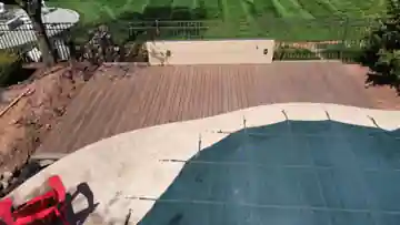 Finished composite pool deck with dark decking beside a swimming pool and surrounding landscape
