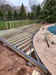Pressure-treated deck framing beside a pool with joist tape applied to framing members before decking installation